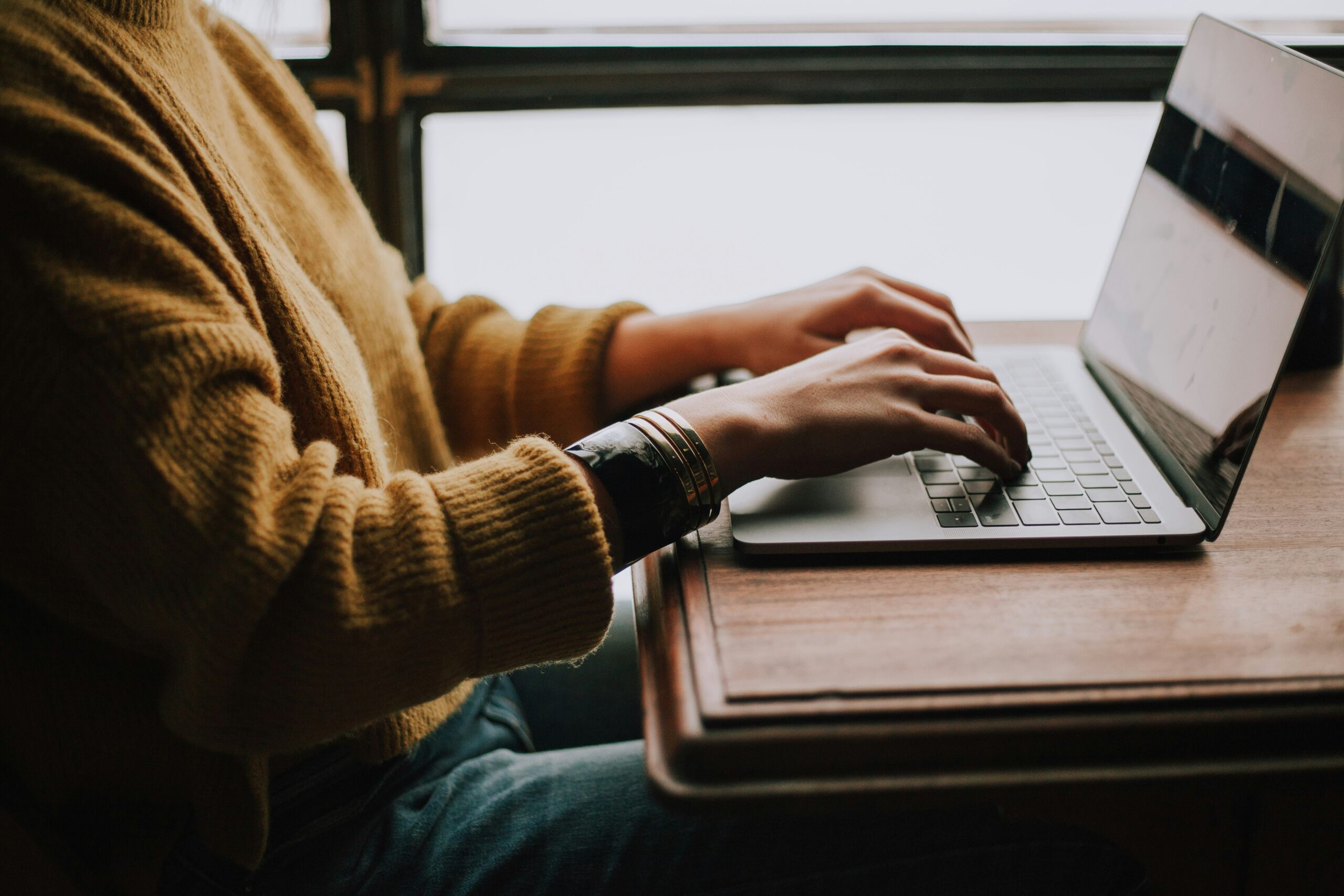 christin-hume-mfB1B1s4sMc-unsplash-scaled.jpg person sitting front of laptop